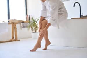 Woman rubs her smooth legs after sclerotherapy in Chevy Chase, MD