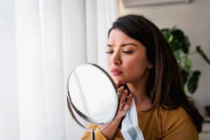 Woman looking in the mirror concerned about holiday acne breakout